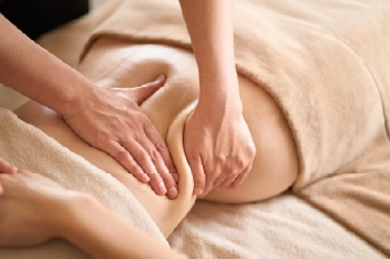 Mulher deitada confortavelmente recebendo uma massagem modeladora por profissional de massoterapia Deisi machado em curitiba